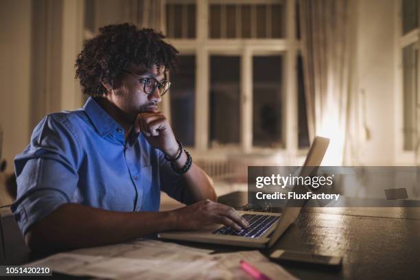 focused black student working on his laptop computer - person taking quiz stock pictures, royalty-free photos & images