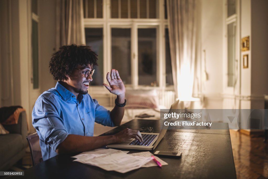 Cheerful student talking over a laptop computer with his friends