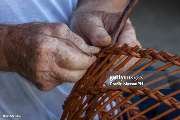 the hands of an old craftsman weave a willow basket - traditional craftsman stock pictures, royalty-free photos & images