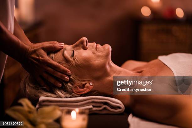 ältere frau, die kopfmassage unkenntlich therapeuten im spa. - kosmetische behandlung stock-fotos und bilder