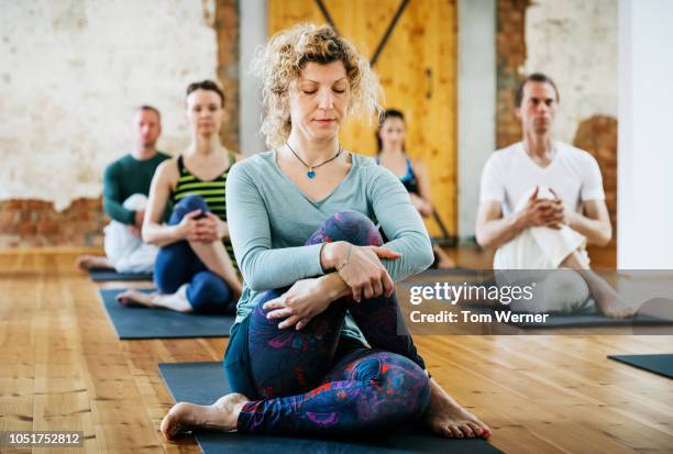 woman meditating while practicing yoga - 40s woman t shirt studio stock pictures, royalty-free photos & images