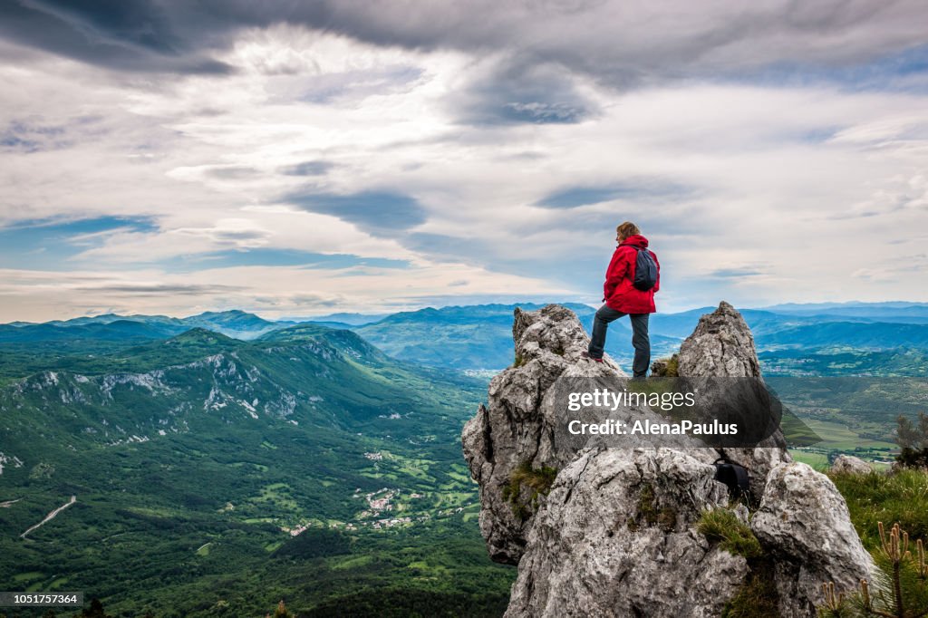 Donna anziana godendo dello straordinario paesaggio in alto in montagna