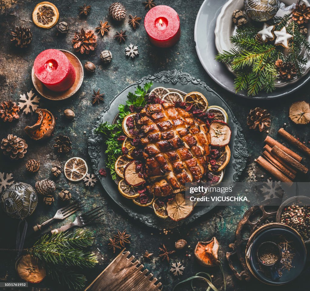 Christmas dinner table with roasted pork ham , flavors, decoration and candles