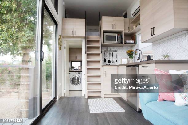 the interior of a tiny house with large glass windows, showcase the kitchen, living room and loft bedroom. - piccolo foto e immagini stock