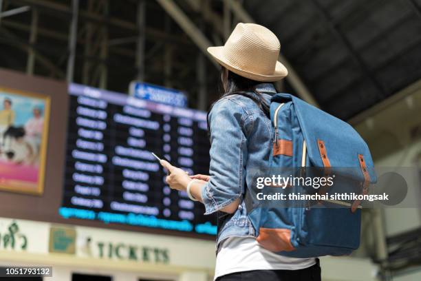 young woman checking her train in timetable board - women reservation stock pictures, royalty-free photos & images