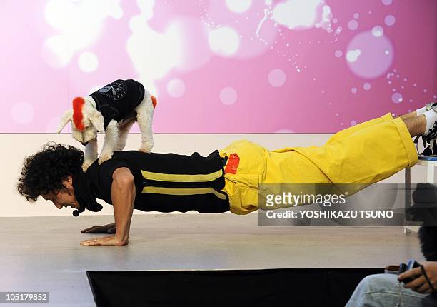 Dog and his trainer perform push-ups during a performance in a break of dog fashion show in Tokyo on October 11, 2010. Some 30 dogs and their owners...