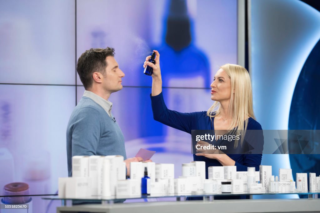Blonde woman applying hair spray to a male colleague
