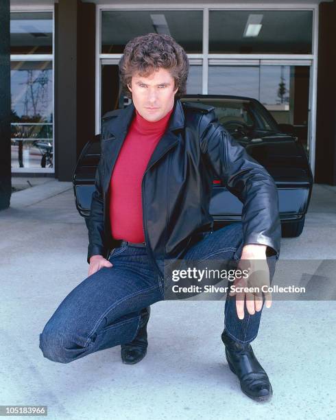 American actor David Hasselhoff, star of the hit tv show 'Knight Rider', circa 1983. Behind him is the artificially intelligent supercar KITT.