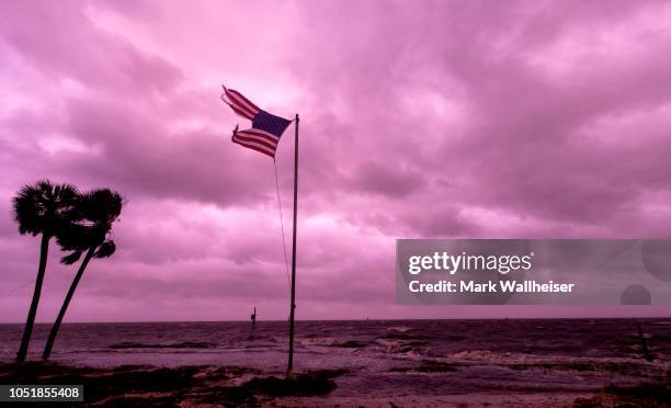 An American flag battered by Hurricane Michael continues to fly in the in the rose colored light of sunset at Shell Point Beach on October 10, 2018...