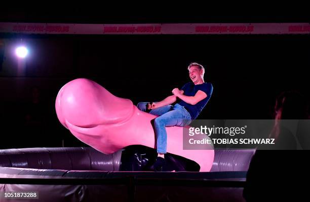 Man rides a giant phallus at the Venus Fair for Erotic Entertainment and Lifestyle during the fair's opening day in Berlin on October 11, 2018.