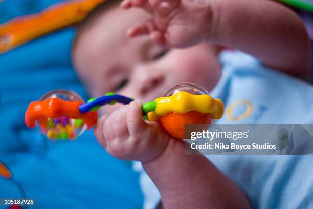 baby playing with rattle - baby rattle stock pictures, royalty-free photos & images