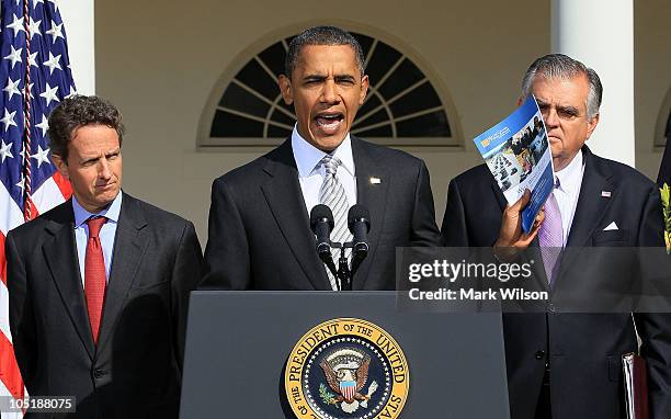 President Barack Obama holds up a book while speaking next to Treasury Secretary Timothy Geithner and Secretary of Transportation Ray LaHood , during...