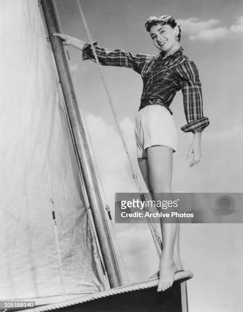 Actress Audrey Hepburn poses barefoot on a sailing boat on the set of the film 'Sabrina Fair', 1954.