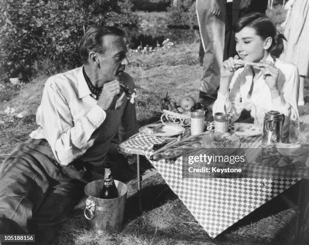 Actors Gary Cooper and Audrey Hepburn share a picnic on the set of the film 'Love in the Afternoon', being filmed on location in Paris, 27th...