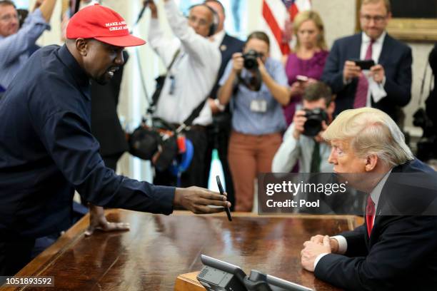 Rapper Kanye West , left, shows a picture of a plane on a phone to U.S. President Donald Trump during a meeting in the Oval office of the White House...