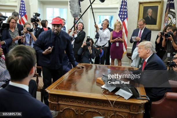Rapper Kanye West, second left, stands up as he speaks during a meeting with U.S. President Donald Trump in the Oval office of the White House on...