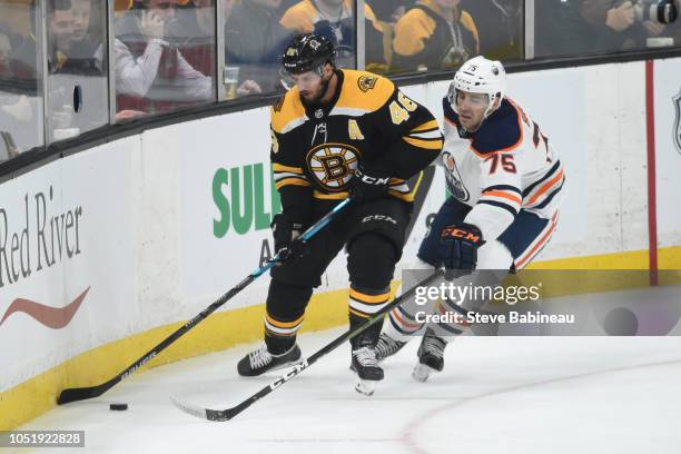 David Krjeci of the Boston Bruins skates with the puck against Evan Bouchard of the Edmonton Oilers at the TD Garden on October 11, 2018 in Boston,...