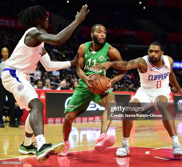 Johnathan Motley and Sindarius Thornwell of the Los Angeles Clippers guard Tre Kelley of Maccabi Haifa as he drives to the basket in the second half...