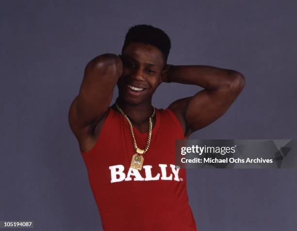 Rapper Doug E. Fresh poses for a portrait session with a fade haircut and wearing a gold medallion and tank top that reads "Bally" in circa 1986