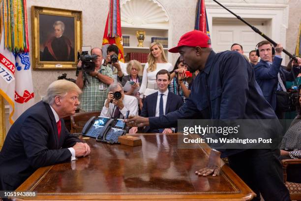 Rapper Kanye West shows President Donald Trump a photo of an airplane in the Oval Office of the White House in Washington D.C. On October 11, 2018.