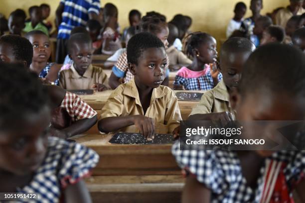 Ivorian schoolchildren attend a class in a village in the southeastern Rubino district, on October 10, 2018. - Yiwo Zone, a non-governmental...