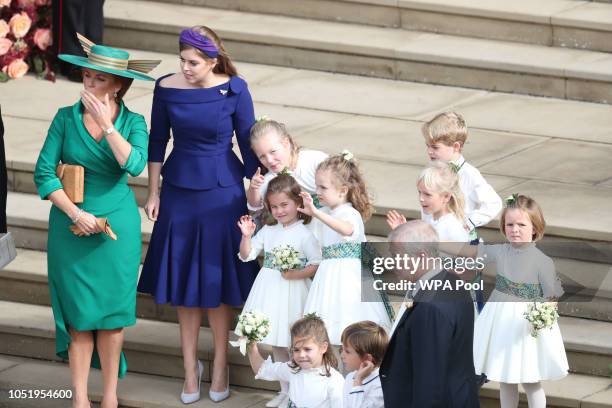 Sarah, Duchess of York and Princess Beatrice of York and the bridesmaids and page boys, including Princess Charlotte and Prince George, wave off...
