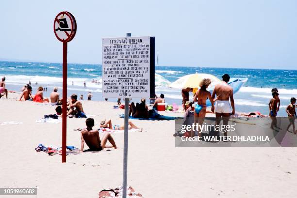 People bath, on January 5, 1987 near a notice board with the rules under which Black people were barred from swimming at the "Whites Only" section at...