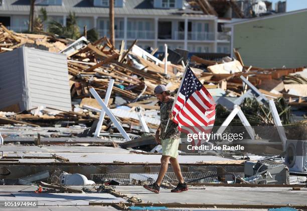 Kevin Guaranta carries an American flag he found as he walks on the foundations of what were homes that were demolished as hurricane Michael passed...