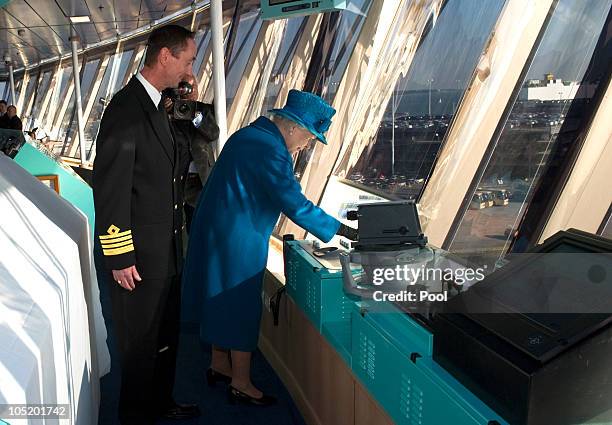 Ship's Captain Chris Wells looks on as Queen Elizabeth II presses the ship's siren during a tour of the Cunard's new cruise-liner Queen Elizabeth II...