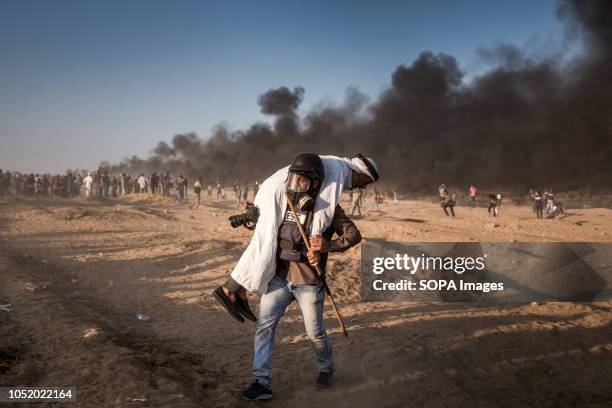 Photojournalist seen carrying an injured elderly protester away from the frontline. Palestinians clash with Israeli forces during a protest calling...