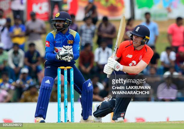 England cricket captain Eoin Morgan is watched by Sri Lankan wicketkeeper Niroshan Dickwella as he plays a shot during the second one day...