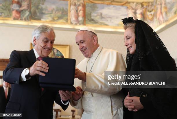 Chile's President Sebastian Pinera and his wife Cecilia Morel exchange gifts with Pope Francis during a private audience at the Vatican on October...