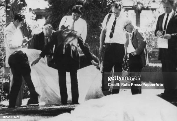 Los Angeles County Coroner Thomas Noguchi takes notes as his assistants remove the sheet from a murder victim on the lawn of Roman Polanski's LA...