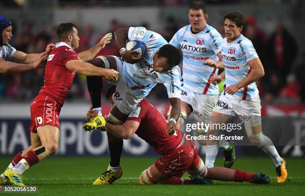 Scarlets players Gareth Davies and Ed Kennedy combine to tackle Racing player Leone Nakarawa during the Champions Cup match between Scarlets and...