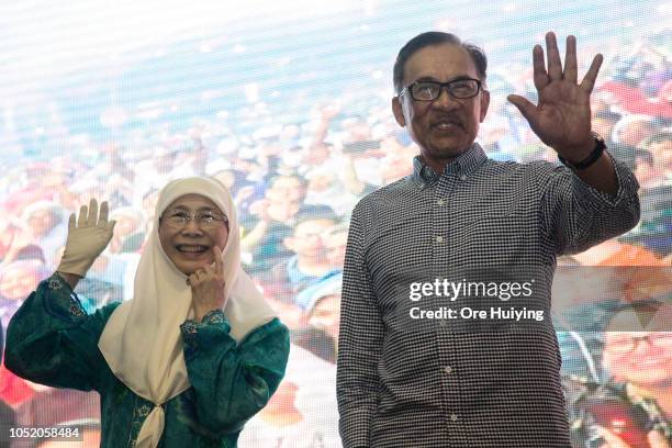 Anwar Ibrahim and his wife Wan Azizah, PKR president and Malaysia's Deputy Prime Minister, wave to his supporters outside the party's headquarters...