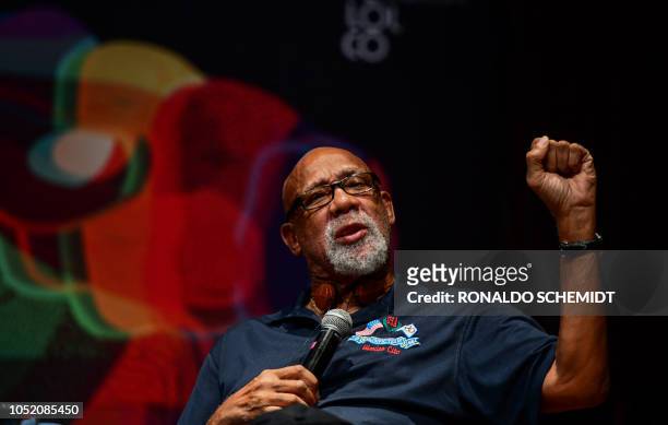 Former US track and field athlete and professional football player John Carlos, raises his fist as he speaks during a conference at the National...