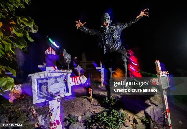 October 2018, Hessen, Muehltal: A monster jumps from the cemetery wall. Since the 1970s, Burg Frankenstein has hosted one of the largest Halloween...