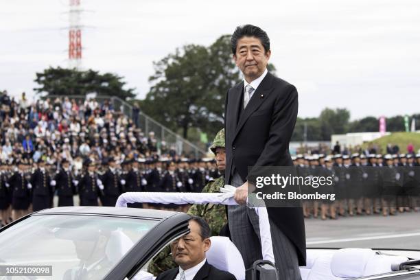 Shinzo Abe, Japan's prime minister, stands in a vehicle as he reviews troops of the Japan Self Defense Forces at Japan Ground Self-Defense Force Camp...