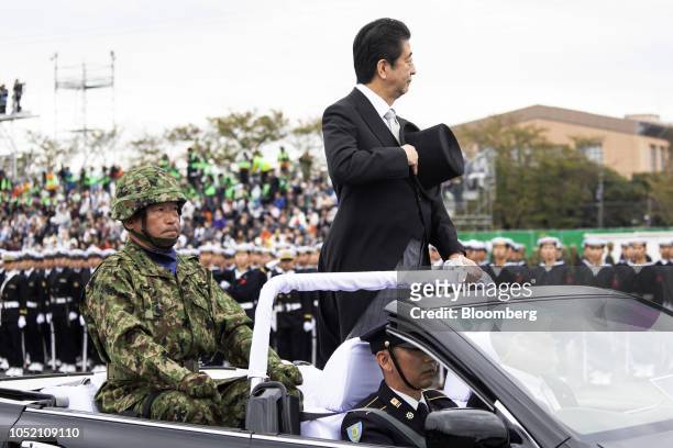 Shinzo Abe, Japan's prime minister, stands in a vehicle as he reviews troops of the Japan Self Defense Forces at Japan Ground Self-Defense Force Camp...