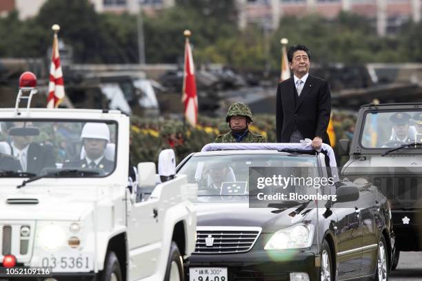 Shinzo Abe, Japan's prime minister, stands in a vehicle as he reviews troops of the Japan Self Defense Forces at Japan Ground Self-Defense Force Camp...