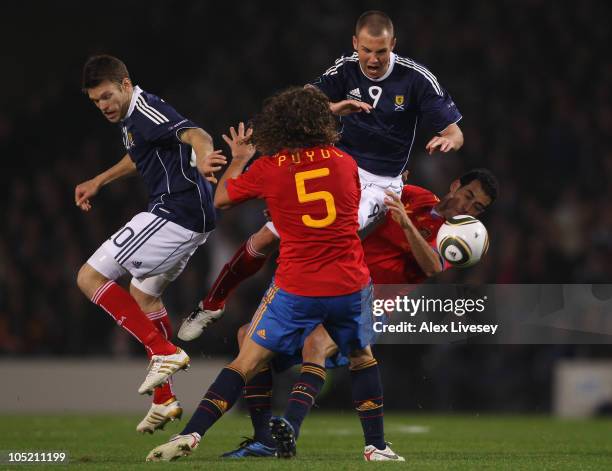 Kenny Miller of Scotland is tackled by Carles Puyol and Sergio Busquets of Spain during the UEFA EURO 2012 Group I Qualifier match between Scotland...