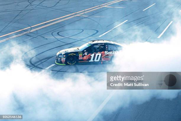 Aric Almirola, driver of the Smithfield Bacon for Life Ford, celebrates with a burnout after winning the Monster Energy NASCAR Cup Series...