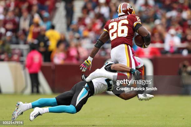 Running back Adrian Peterson of the Washington Redskins loses his shoe as he rushes past strong safety Eric Reid of the Carolina Panthers during the...