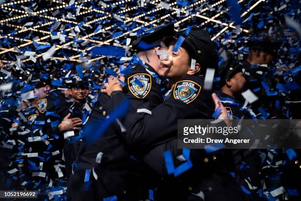 New members of the New York City Police Department embrace at the conclusion of their police academy graduation ceremony at the Theater at Madison...