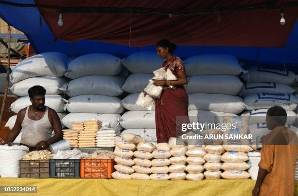 Indian vendors arrange rice pop packets at her stall at a wholesale market during the Durga Puja festival in Chennai on October 16, 2018. - The...