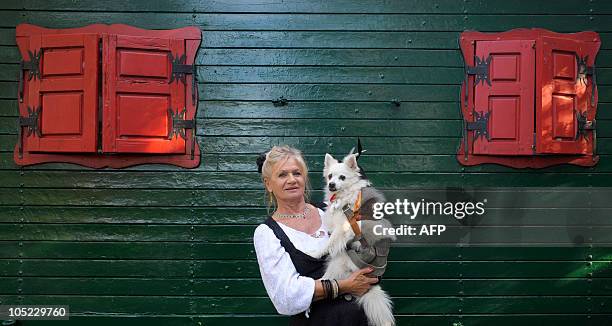 German dressmaker Hildegard Bergbauer poses with her spitz dog "Spitzerich" wearing a collar with sausages and a traditional Bavarian style...