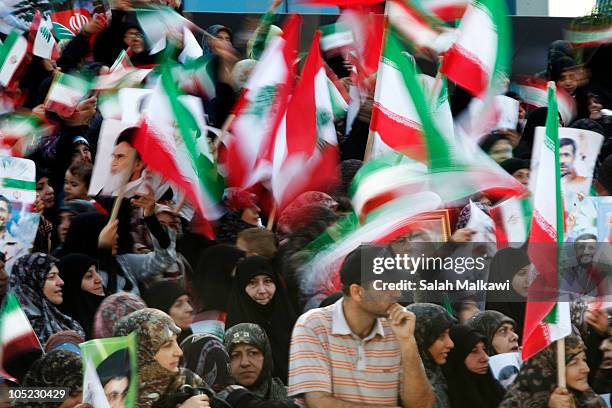 Lebanese people wave flags as Iranian President Mahmoud Ahmadinejad arrives in southern suberb of Beirut on October 13, 2010 in Lebanon. The...