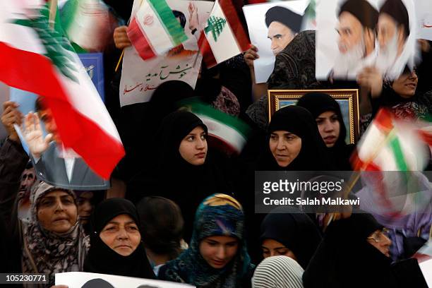 Lebanese people wave flags and hold portraits of Iranian President Mahmoud Ahmadinejad as he arrives in southern suberb of Beirut on October 13, 2010...