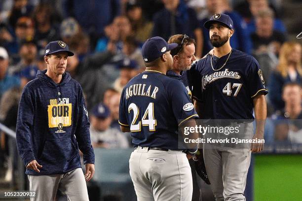 Gio Gonzalez of the Milwaukee Brewers is looked at by the trainer and manager Craig Counsell after being injuried during the second inning against...