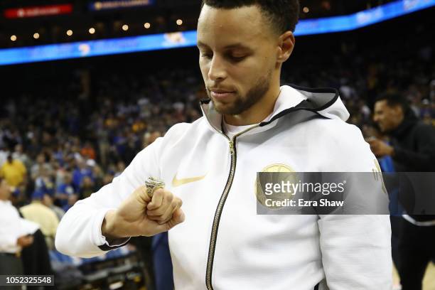 Stephen Curry of the Golden State Warriors looks at his 2017-2018 Championship ring prior to their game against the Oklahoma City Thunder at ORACLE...